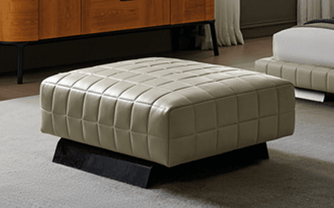A modern quilted leather ottoman with a low-profile base