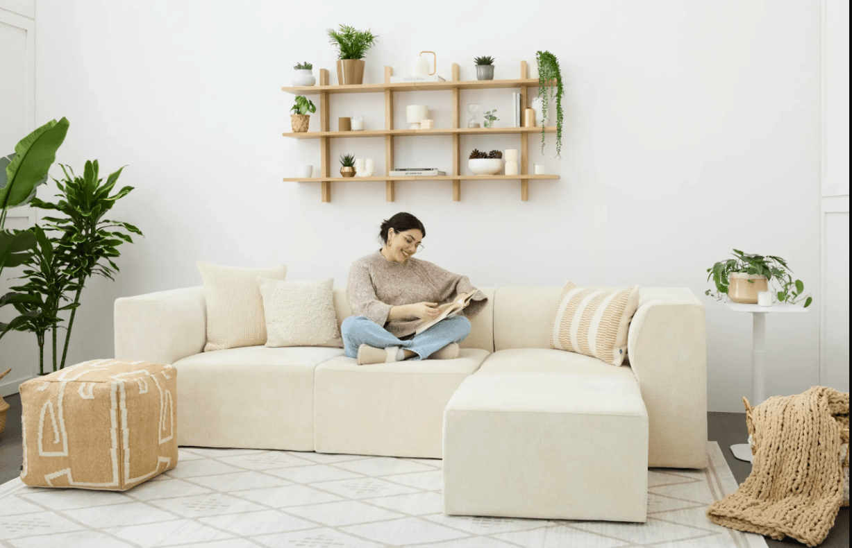 a young woman relaxes on a cozey couch in a minimalist living room, reading a book